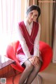 A woman sitting on a red chair in a room.