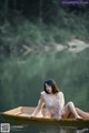 A woman sitting in a boat on a lake.