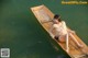 A woman sitting in a wooden boat on the water.