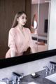 A woman standing in front of a mirror in a bathroom.