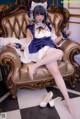 A woman in a maid outfit sitting on a chair.