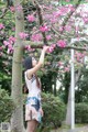 A woman standing under a tree with pink flowers.